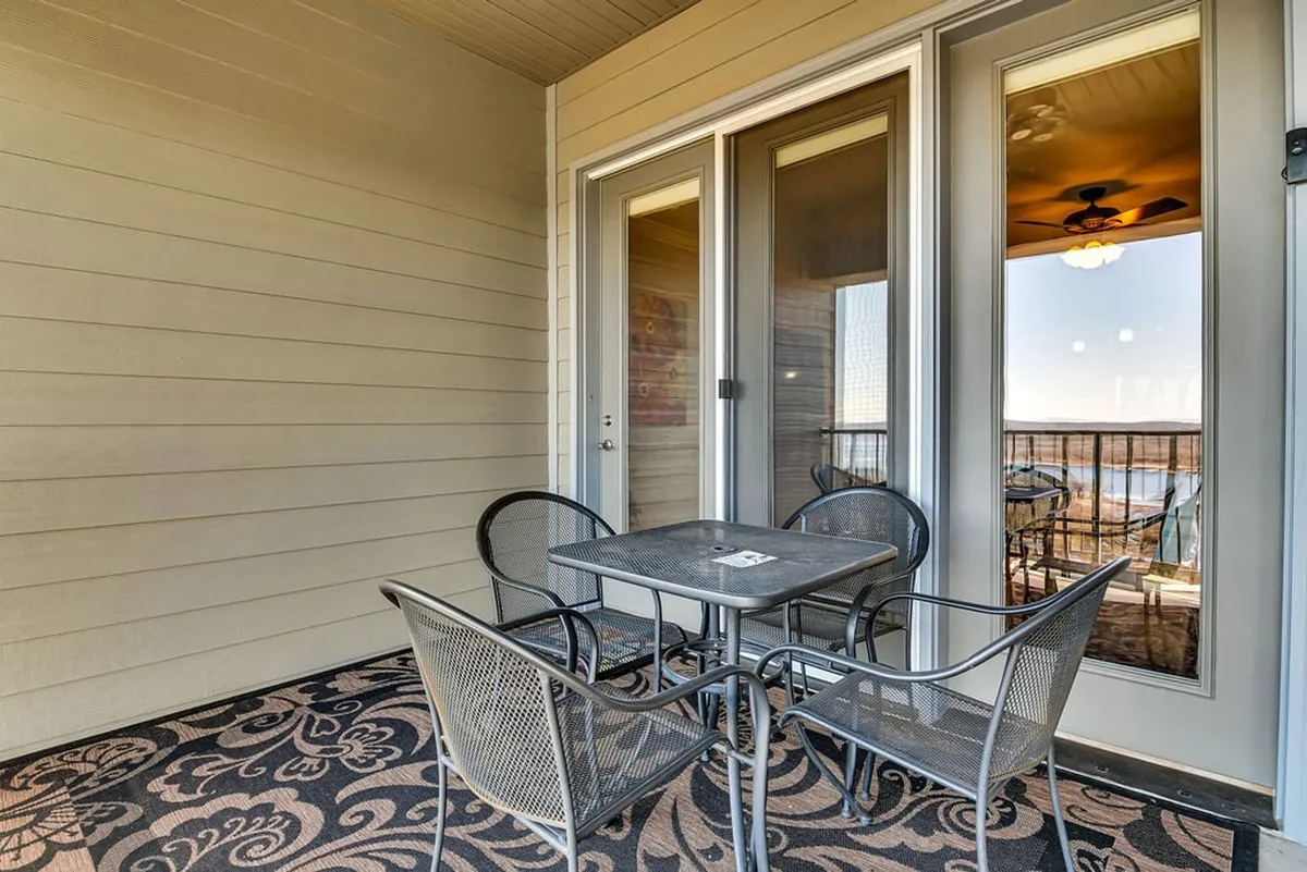 A cozy outdoor seating area featuring a table and chairs set on patterned flooring, positioned just outside glass doors. The mood is tranquil, ideal for morning coffee or quiet evening conversations.