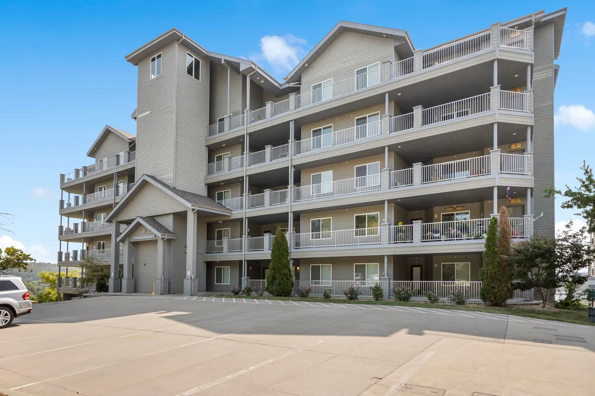 A multi-story building with multiple balconies set amid well-maintained landscaping. The image conveys a welcoming atmosphere, highlighting accessible entryways and inviting communal spaces. The sunset light adds to the sense of tranquility and leisure, with the balconies suggesting private outdoor relaxation options.